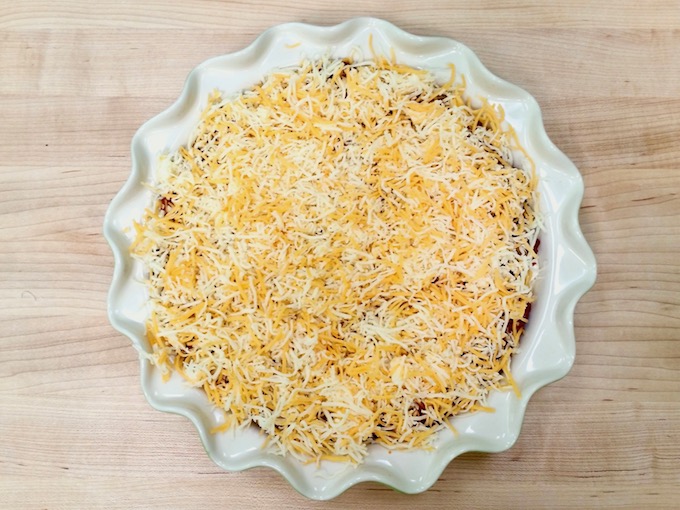 Shredded cheese layered on top of ground beef for taco dip..