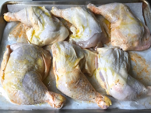 Tops of chicken leg quarters drizzled with olive oil.