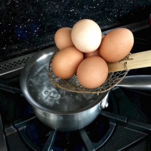 Adding eggs to boiling water.