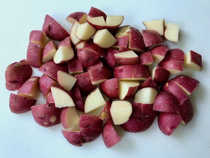 Red potatoes cubed on cutting board.