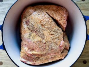 Placing pork butt in dutch oven.