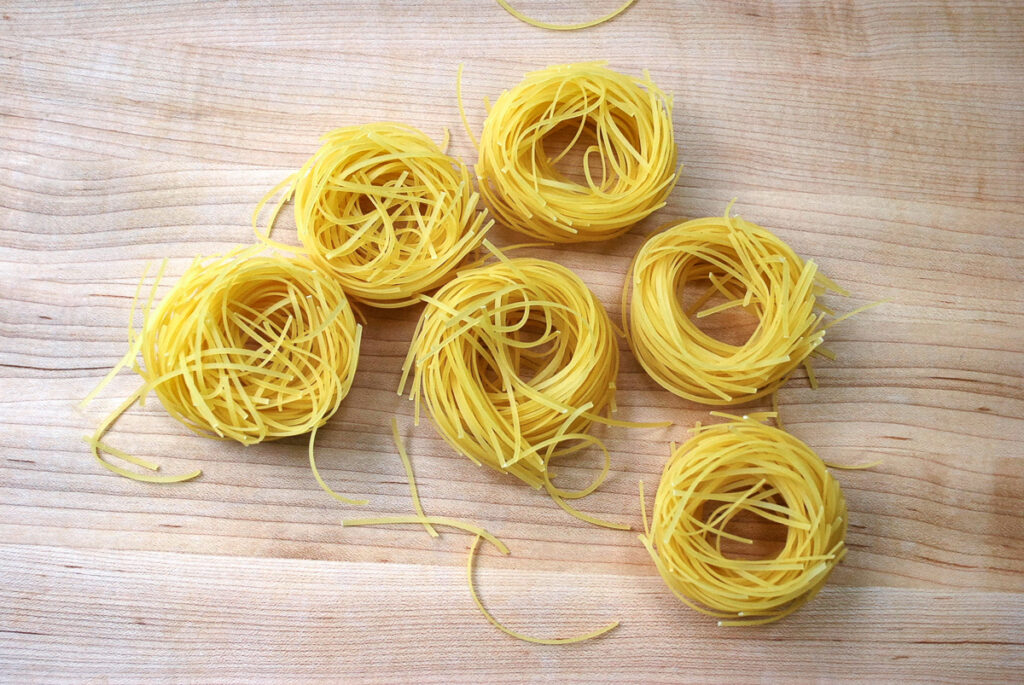 Rounds of angel hair pasta on a board.