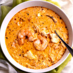A bowl of Peruvian shrimp soup in a white bowl.