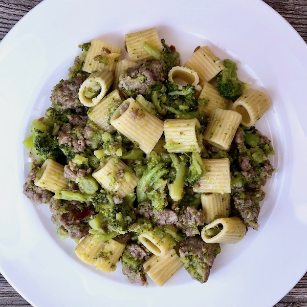 A plate of sausage broccoli and pasta.