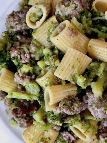 A plate of sausage broccoli and pasta.
