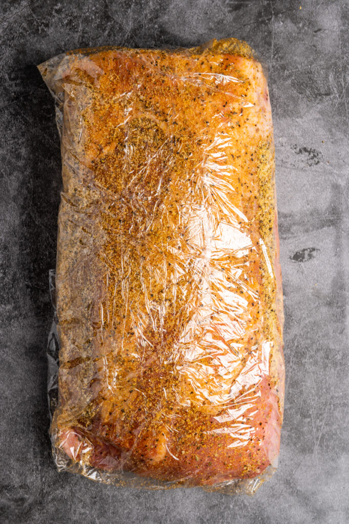 A seasoned pork loin wrapped in plastic.