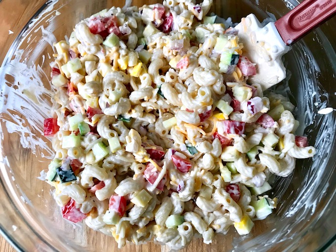 Mixing together the macaroni salad in a bowl.