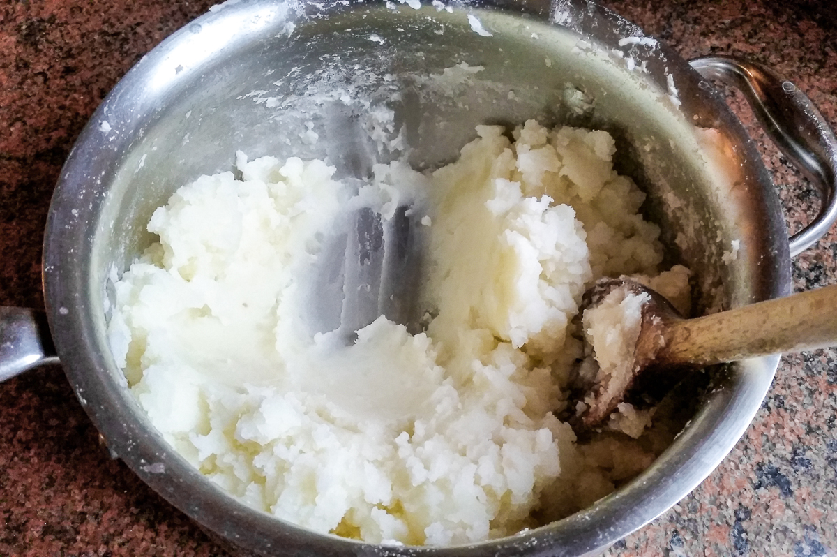 A pot of mashed potatoes with the bottom scraped to show excess water evaporated.