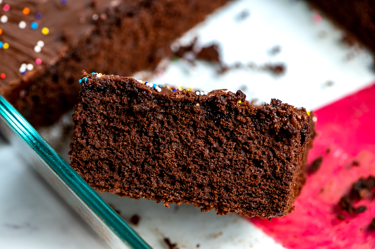 A side view of a slice of chocolate sheet cake in a pan.