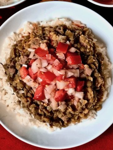 A plate of rice and lentils topped with tomato onion dressing.