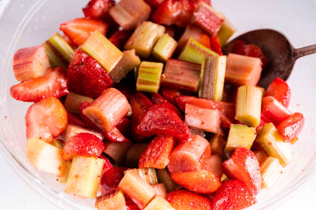 Strawberry and rhubarb mixed with sugar in a bowl.