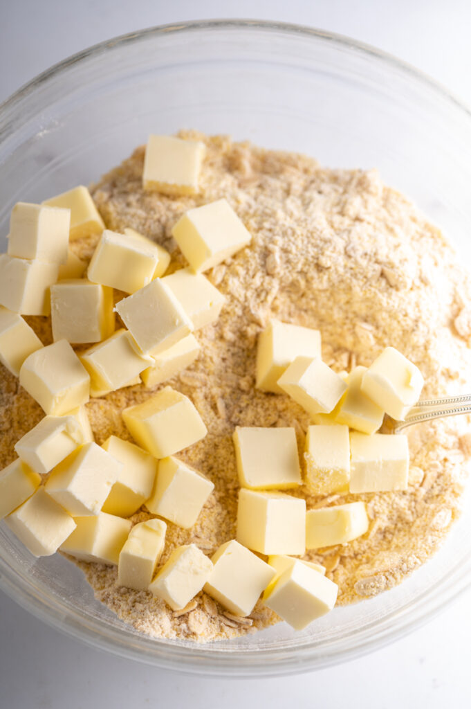 Cubes of butter on top of dry mixture in a bowl.