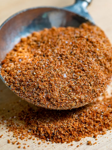 BBQ Spice in a pewter measuring cup spilling over onto board.