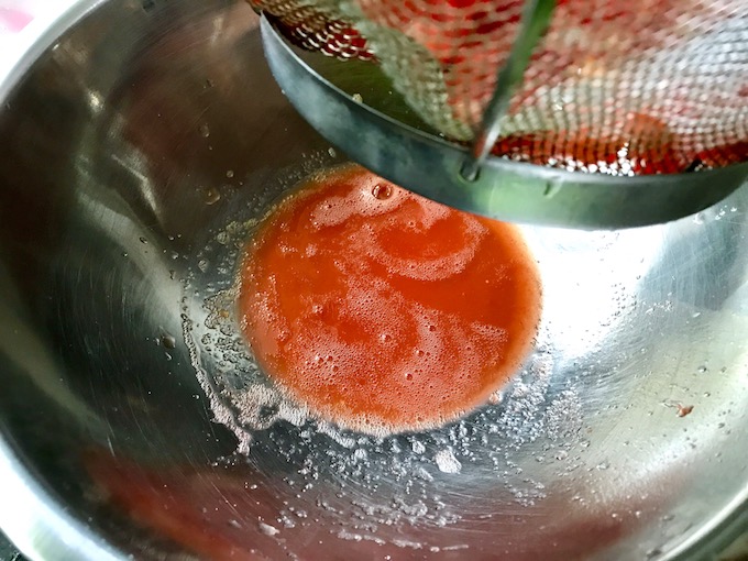 Tomato liquid leftover in bowl from straining diced tomatoes.