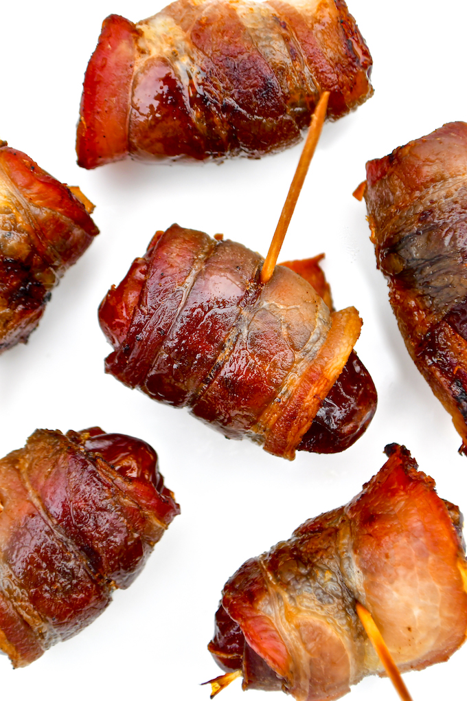 Bacon wrapped dates on a baking sheet.