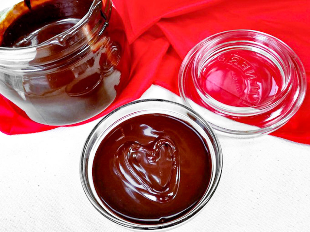 A jar of chocolate syrup with a heart shape.