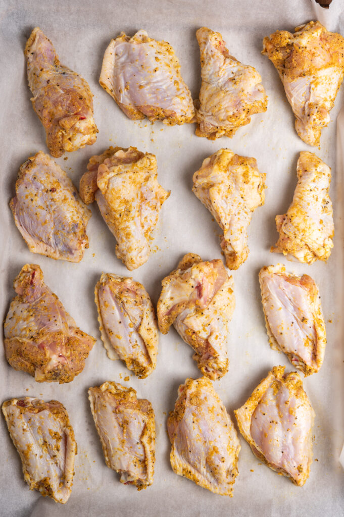 Arranged chicken wings ready to cook on a baking sheet.