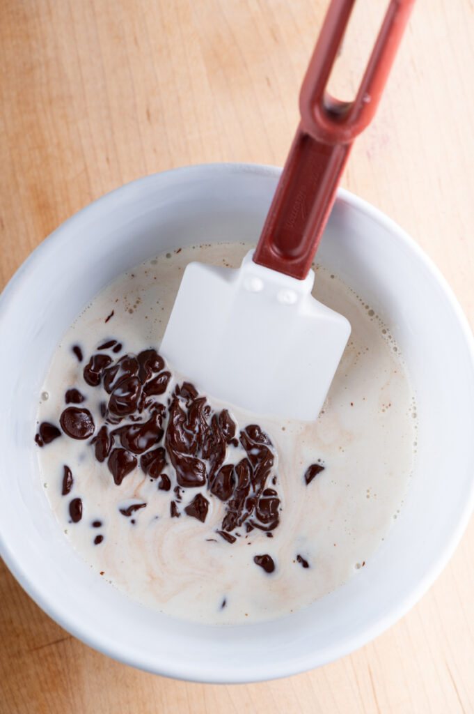 Hot cream poured over chocolate chips in a bowl.