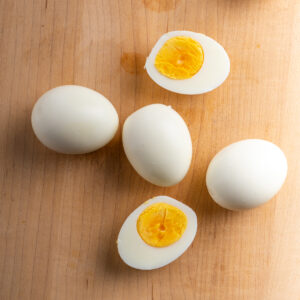Boiled peeled eggs with some sliced on a board.