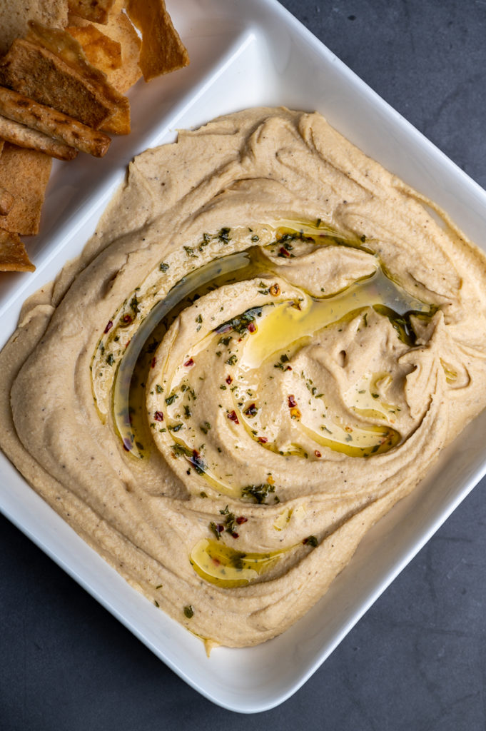 Hummus dressed with olive oil and spices on a platter.
