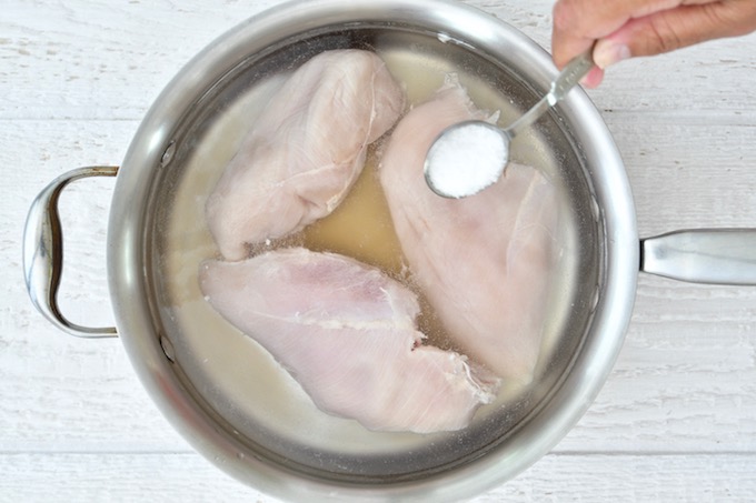 Adding salt to water for poaching chicken.