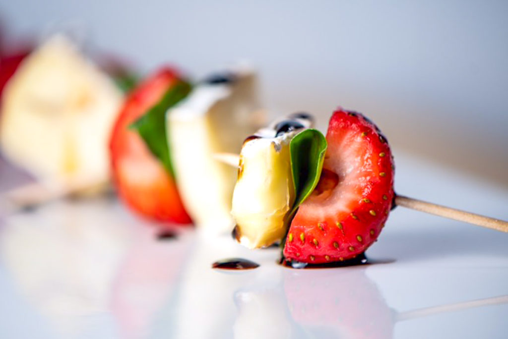 Strawberry with a piece of brie and a basil leaf.