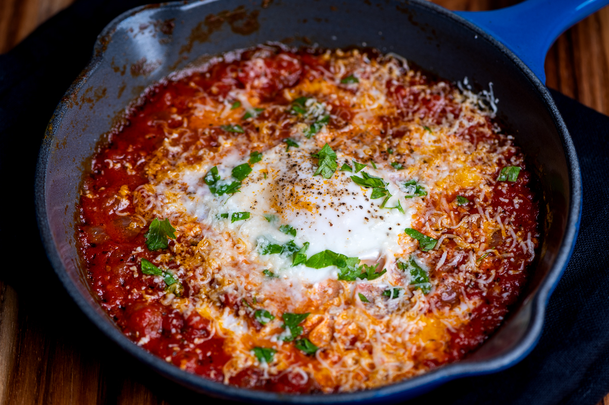 An egg poached in tomato sauce in a skillet.