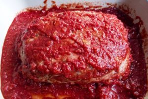 Italian meatloaf coated with tomato sauce.