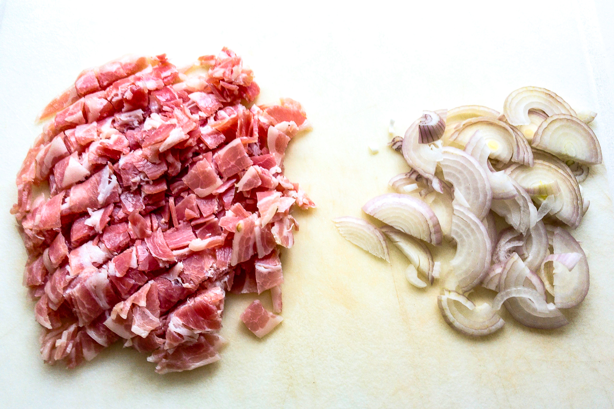 Diced pancetta and shallots on a cutting board.