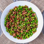 Peas and pancetta in a white bowl.