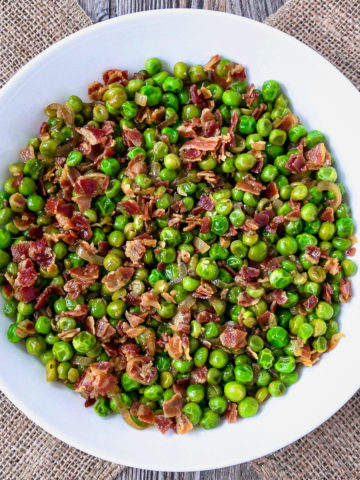 Peas and pancetta in a white bowl.