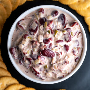 New England bean dip in a bowl surrounded by crackers.