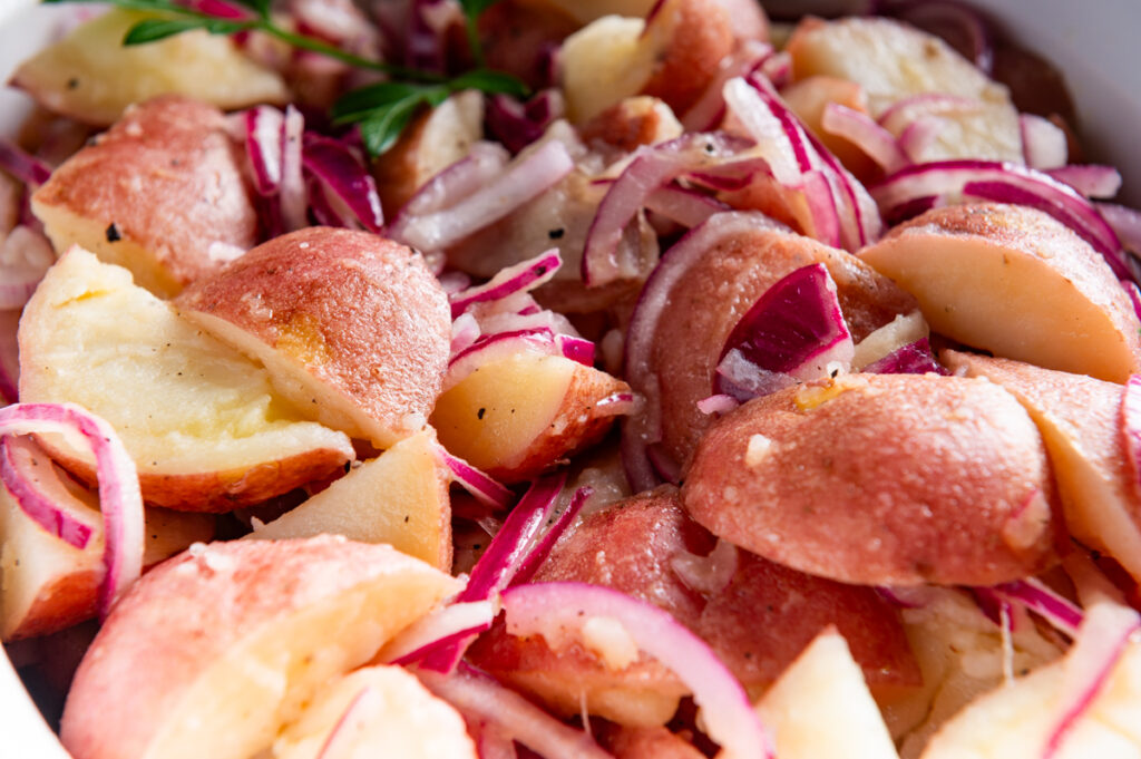 Red potatoes tossed with red onions in a bowl.