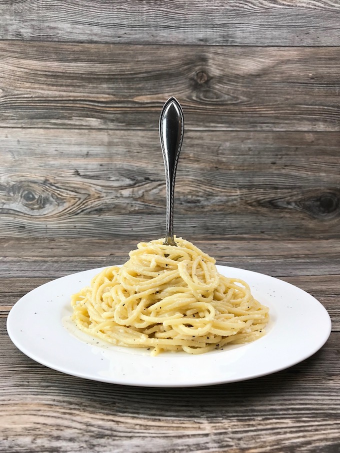 Spaghetti with Garlic Butter and Cheese on a plate with a fork standing up in the middle of it.