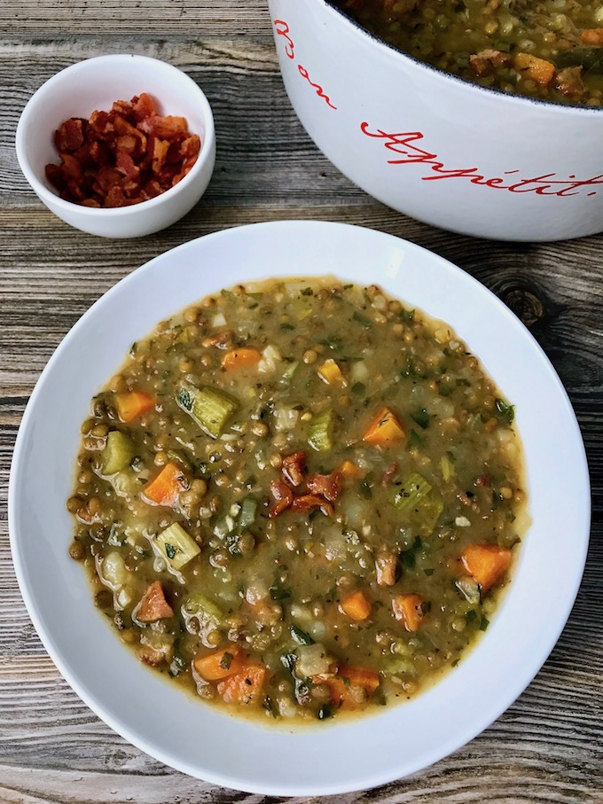A bowl of French lentil soup and a small bowl of bacon bits.