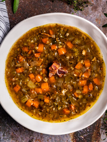 A bowl of French lentil soup garnished with bacon.