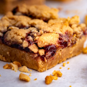 A peanut butter and jelly bar with some peanuts sprinkled around it.