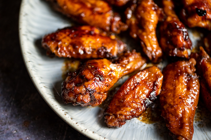 Closeup of sticky teriyaki chicken wings arranged on a plate.