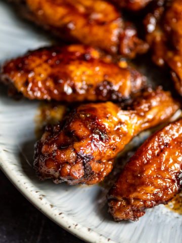 Closeup of sticky teriyaki chicken wings arranged on a plate.
