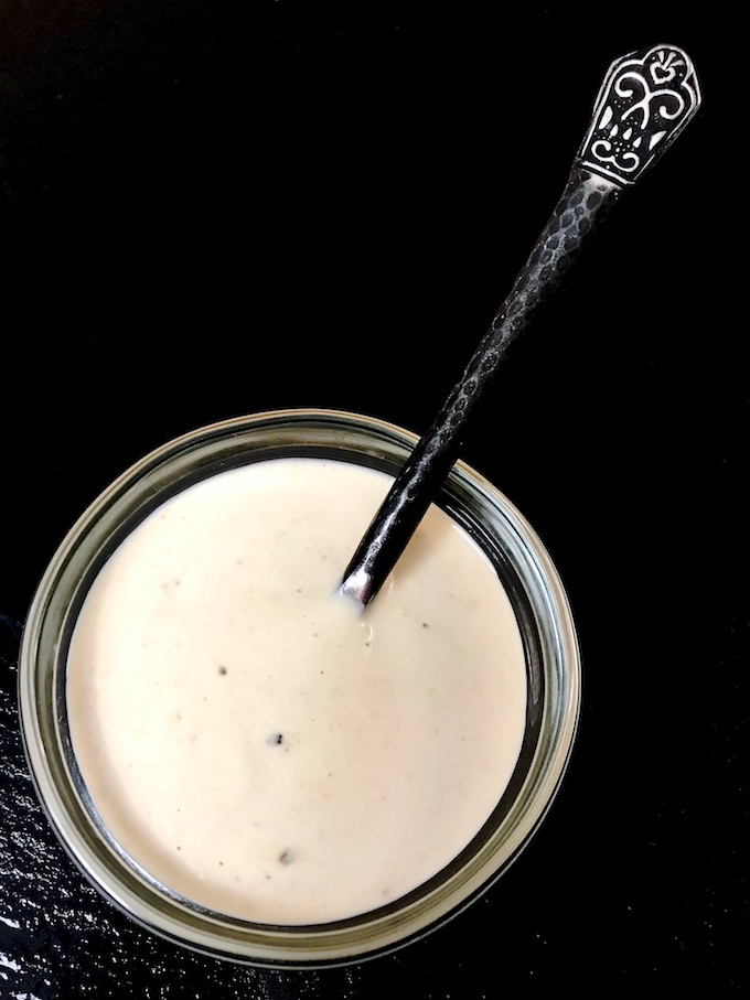 A small bowl of homemade horseradish sauce on a black background.