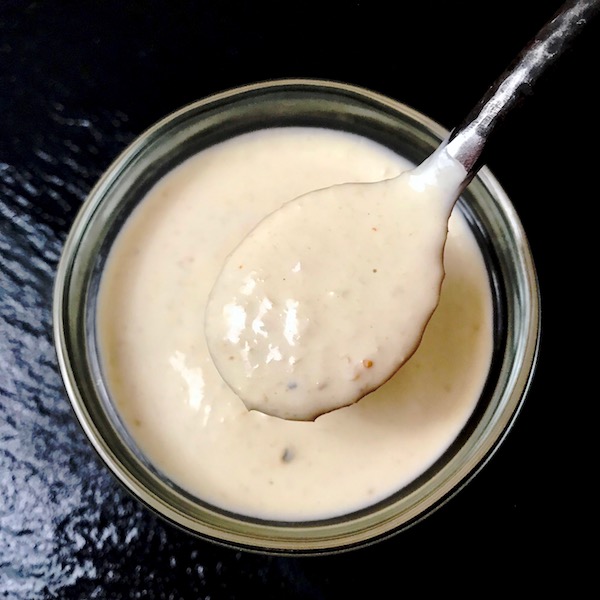A small bowl with a spoonful of homemade horseradish sauce on a black background.
