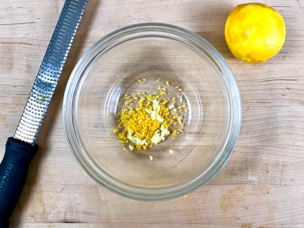 Grated lemon zest and garlic in a bowl.