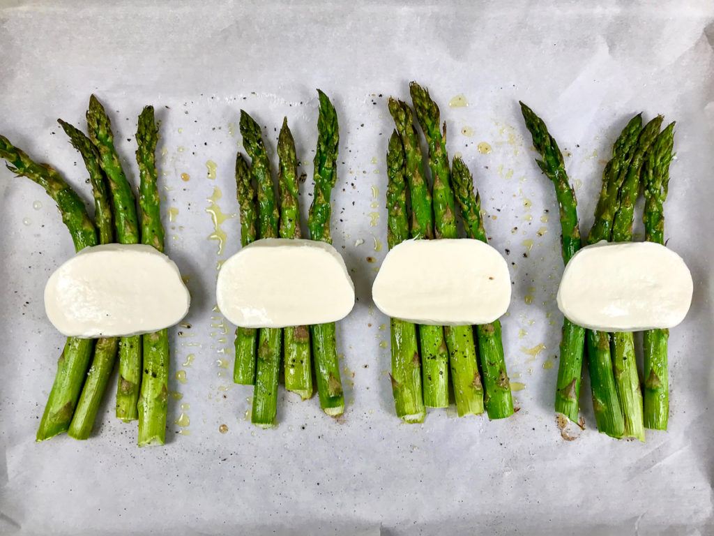 Placing fresh mozzarella onto roasted asparagus.
