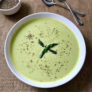 A bowl of cream of asparagus soup sprinkled with pepper.