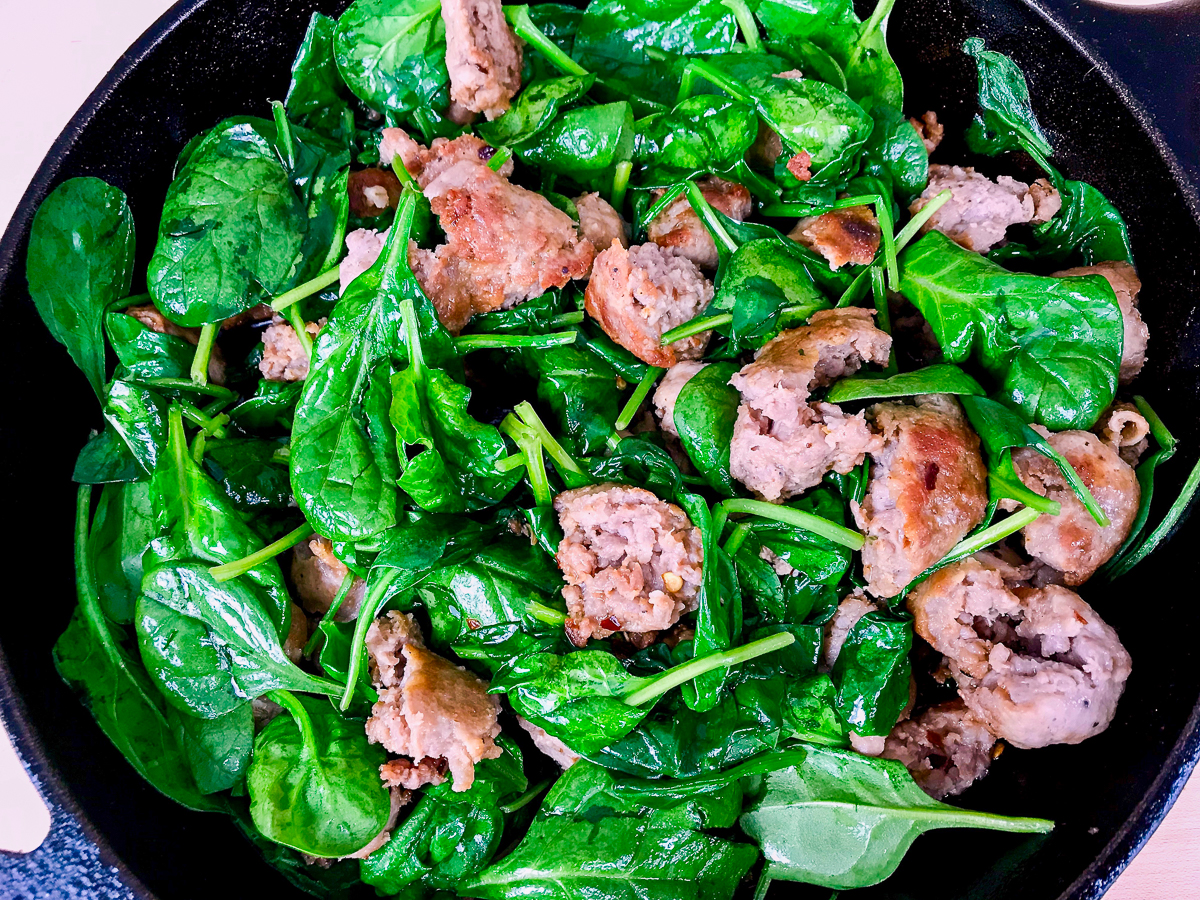Sausage and spinach in a skillet.