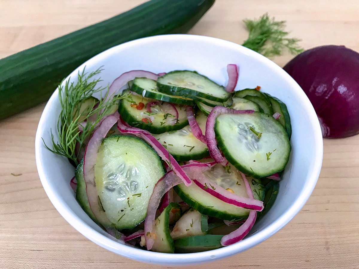 Angle view of a bowl of cucumber salad in a white bowl.