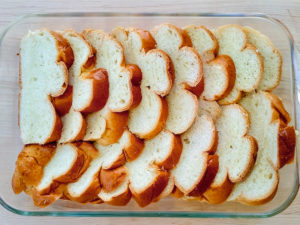 Sliced Challah bread layered in a baking dish.