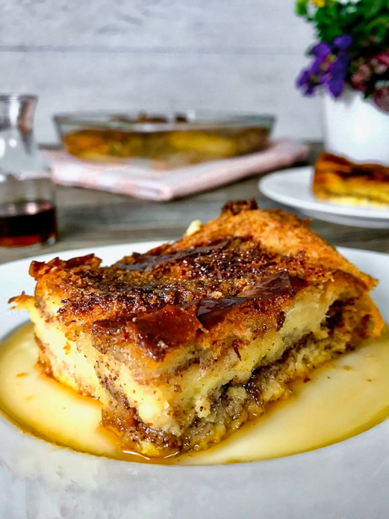 A slice of French toast casserole with maple syrup on a plate.
