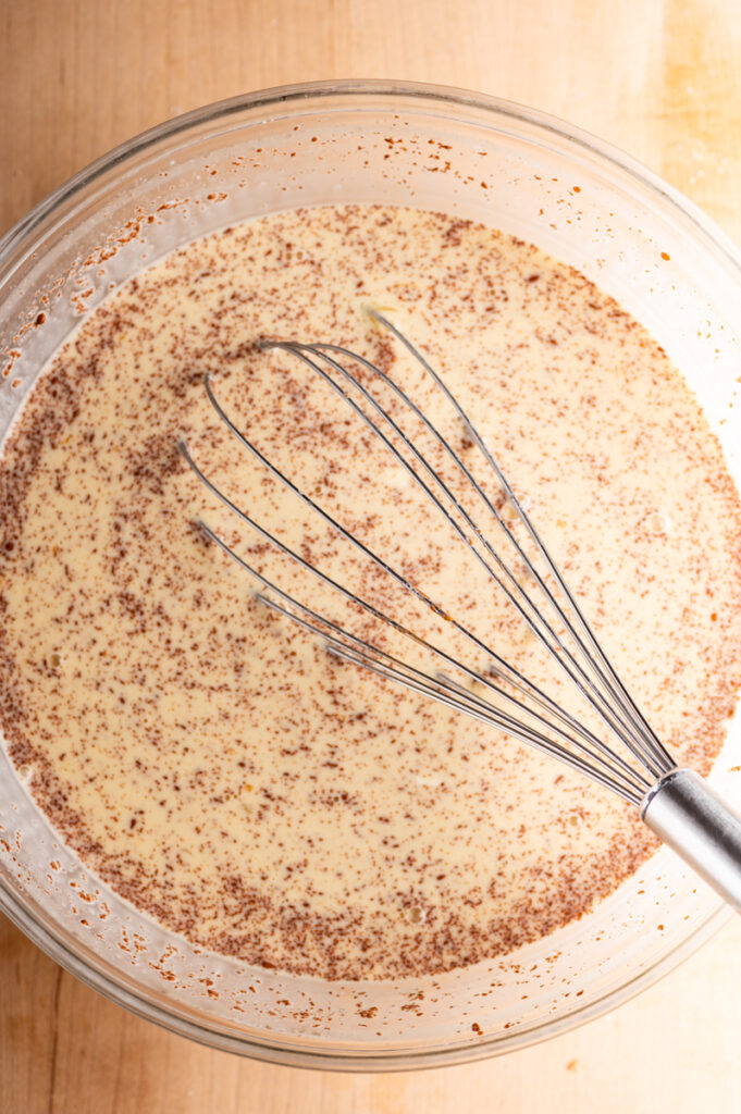 Cream mixture in a bowl with a whisk.