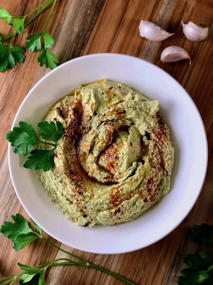 A bowl of parsley hummus sprinkled with paprika.